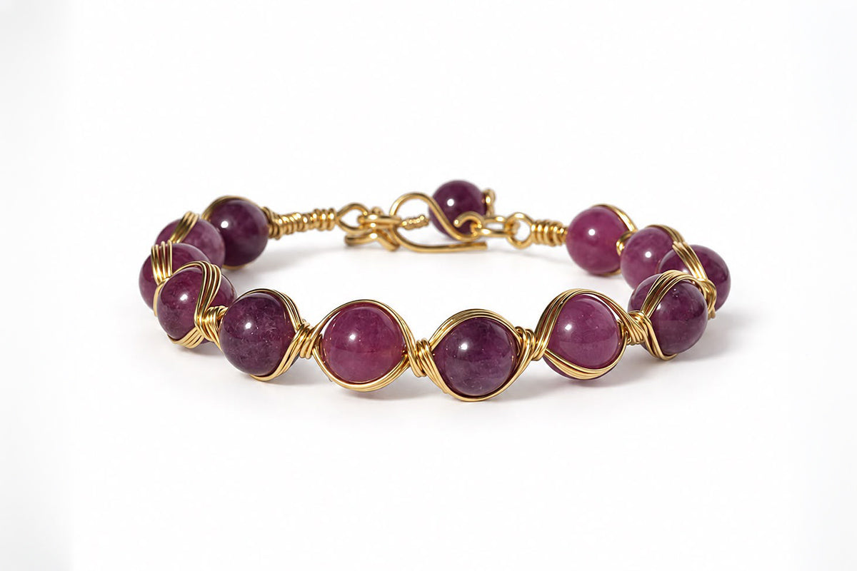 Pulsera de piedras naturales moradas engarzadas una a una con hilo dorado, sobre fondo blanco