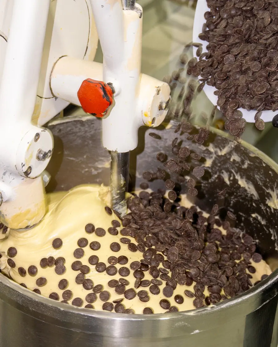 Las escamas de chocolate cayendo sobre la masa en la amasadora del obrador